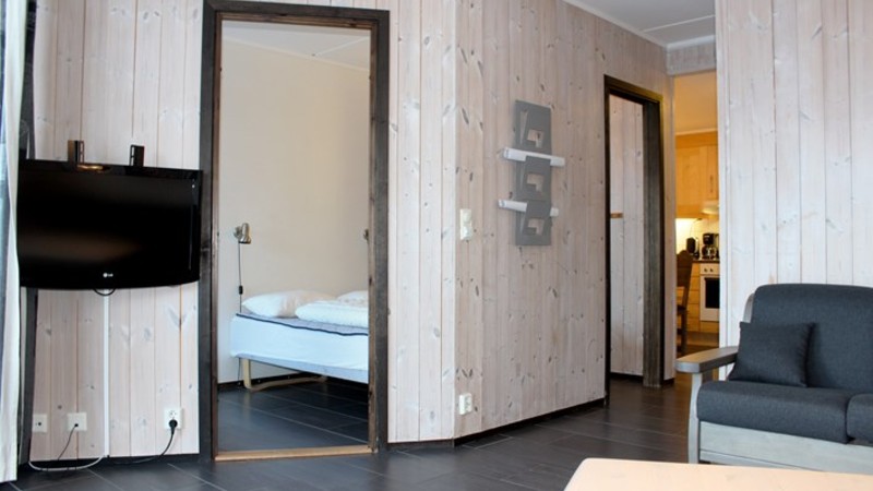 Allrum med soffa och TV. Sovrummet med dubbelsäng har 2 dörrar till samma rum.